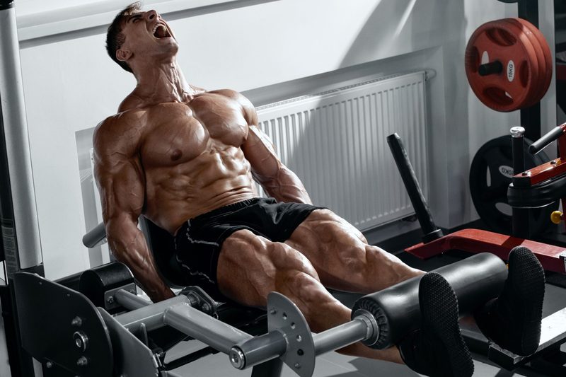 Man doing leg curl exercise on gym seated machine