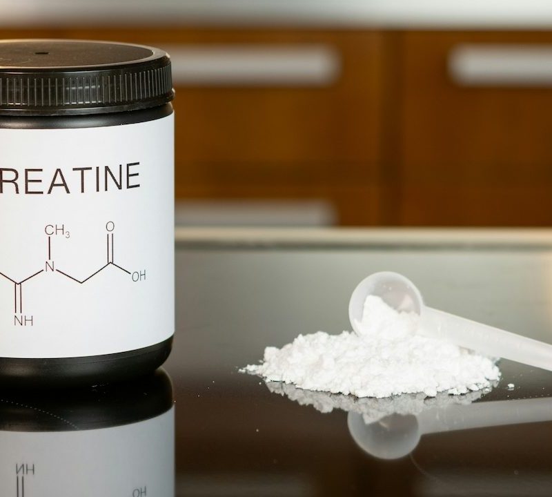 Creatine powder with some on table with a spoon