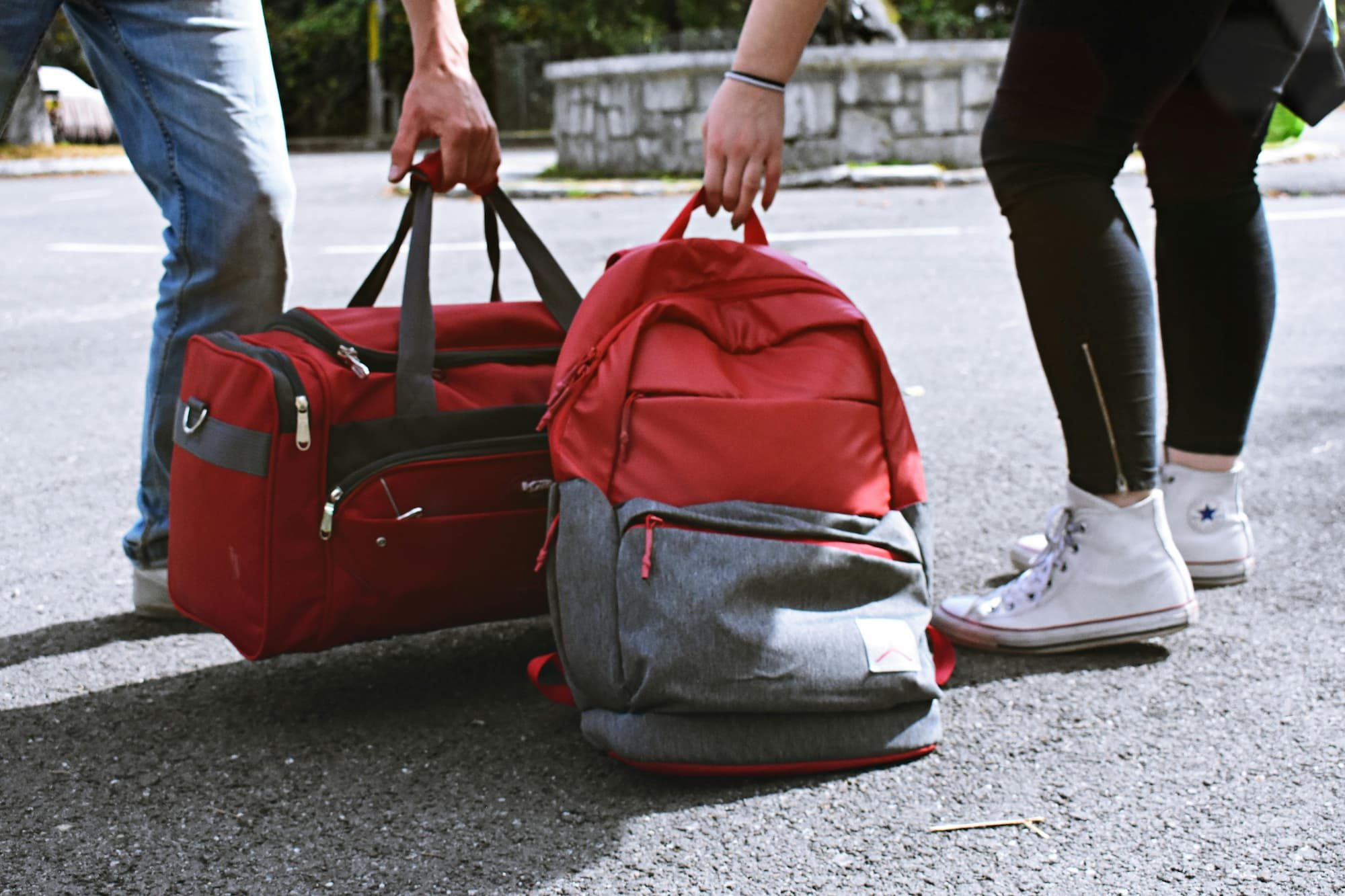 someone carrying a duffel bag and someone carrying a backpack next to each other