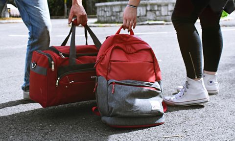 someone carrying a duffel bag and someone carrying a backpack next to each other