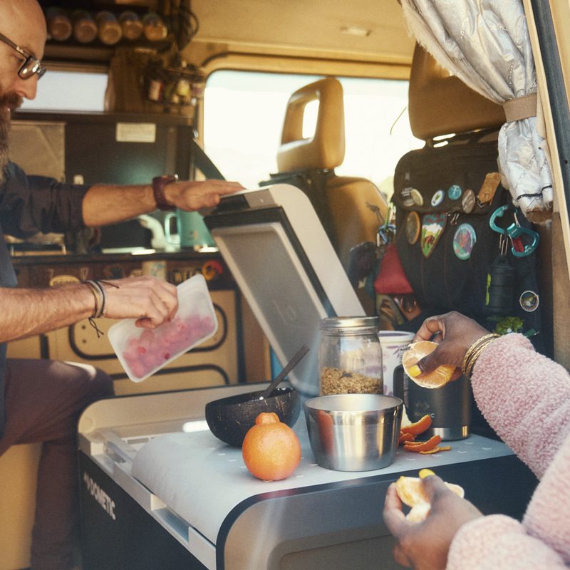 Couple using a Dometic portable refrigerator while car camping.