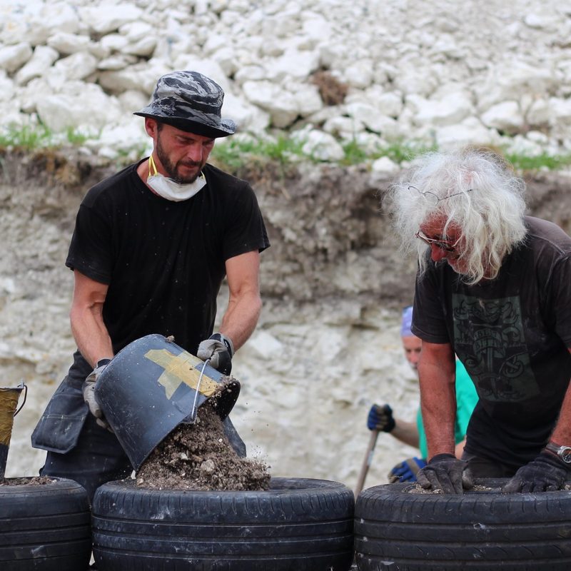 two men filling tires with dirt to build an Earthship