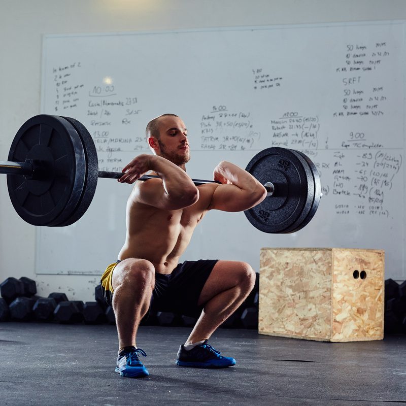 Man doing front squats shirtless