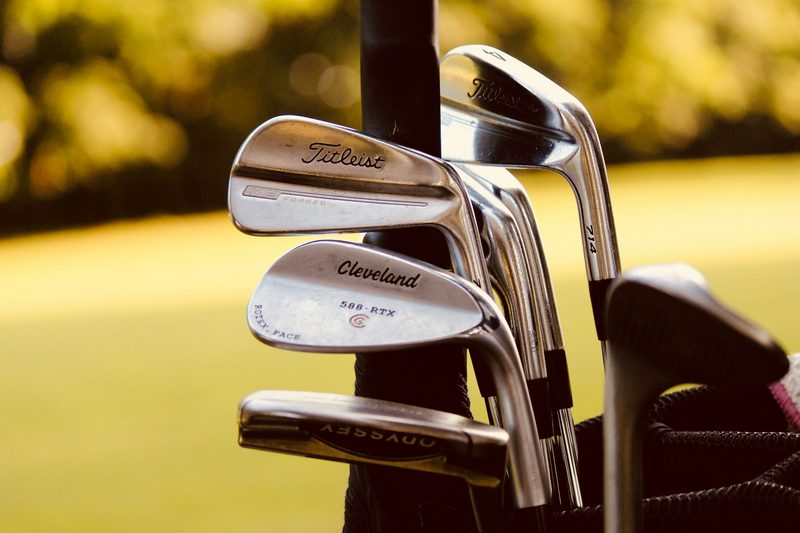 Golf clubs in a golf bag on a golf course.