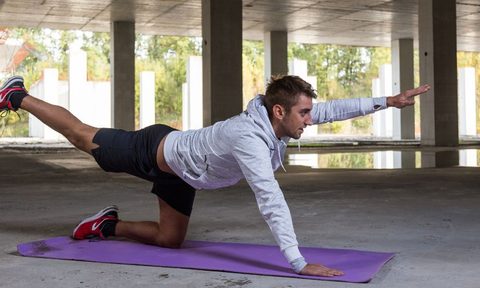 man in gray sweatshirt doing the bird dog exercise
