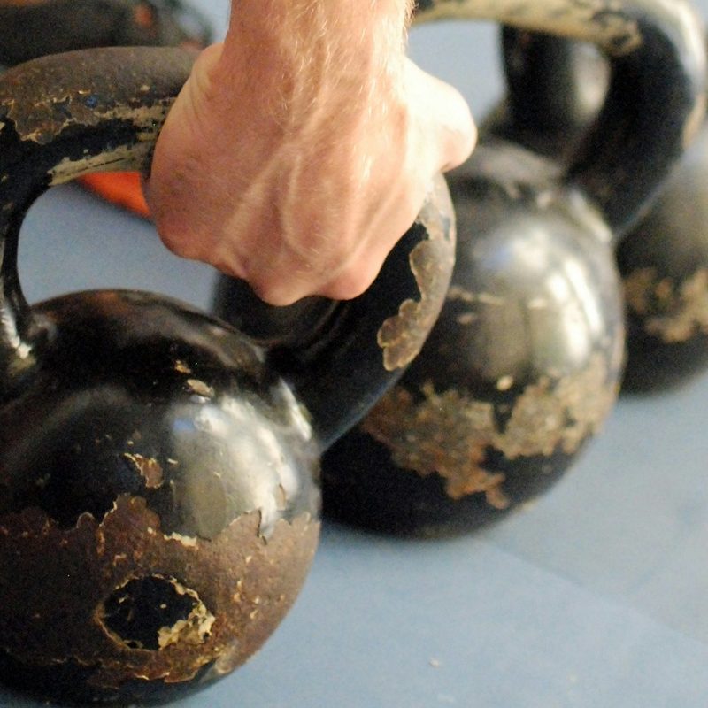Man picking up kettlebell just hand and leg close up view in gym