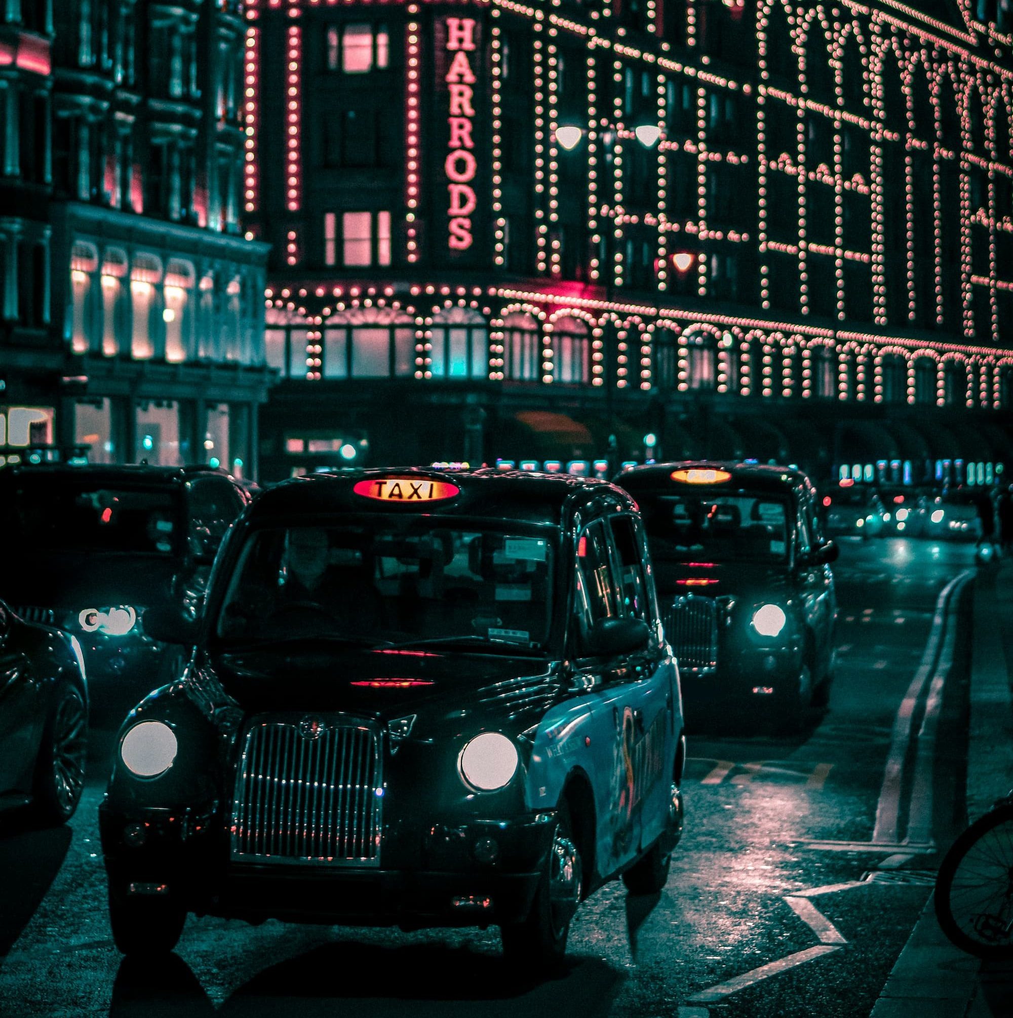 black taxi in the street passing through harods mall during nighttime