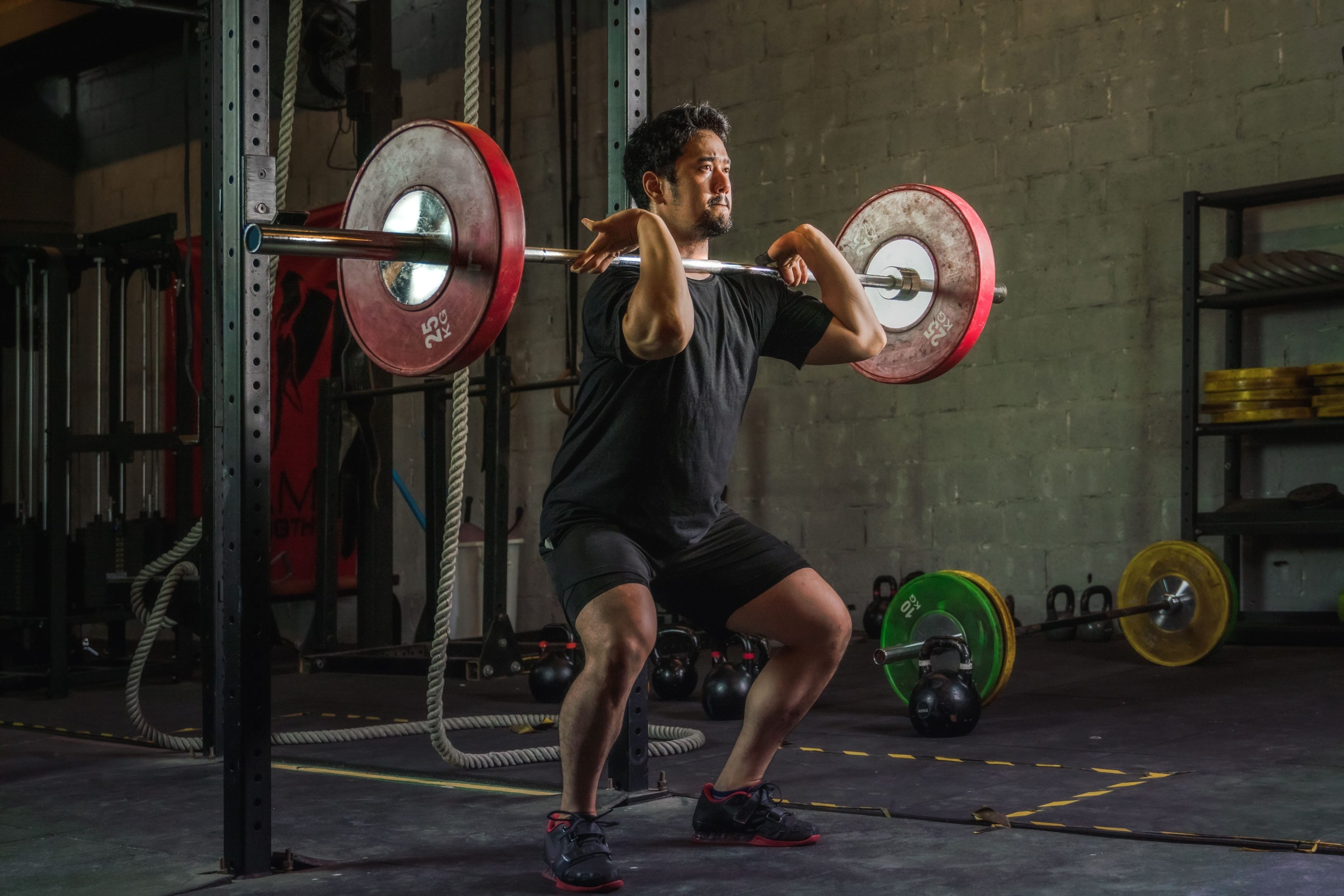 red weights Athletic man having workout and bodybuilding with barbells weight front squat setting style in gym and fitness club in dark tone