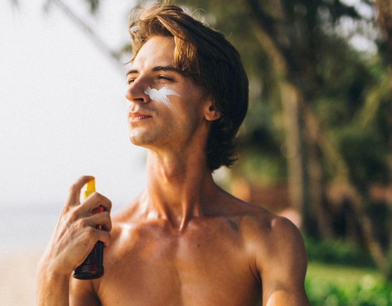 Man applying spray sunscreen at beach