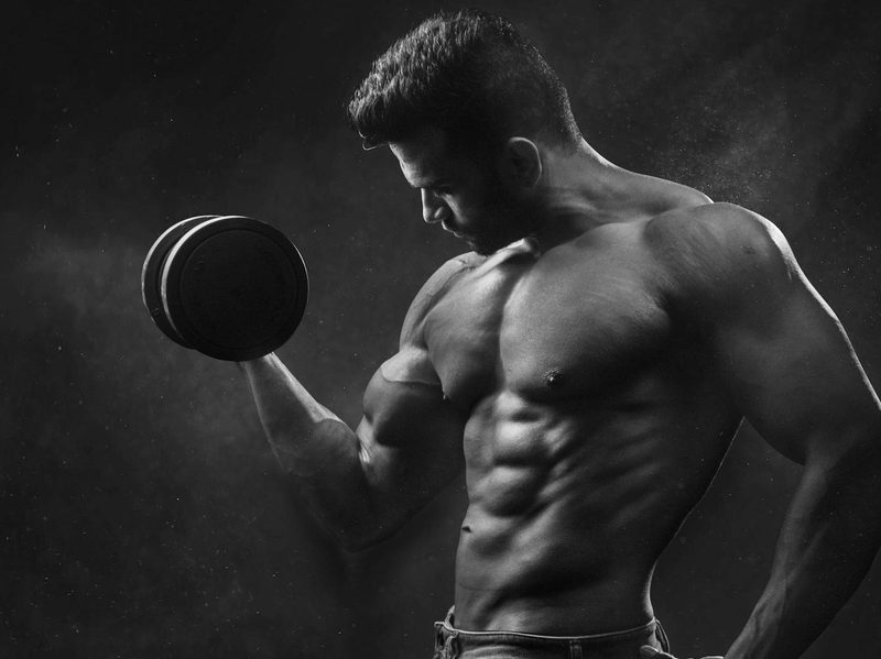 Muscular man bicep curling weight in one hand