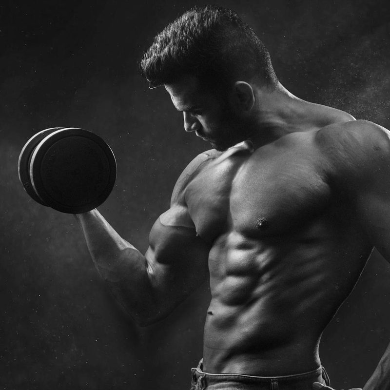 Muscular man bicep curling weight in one hand