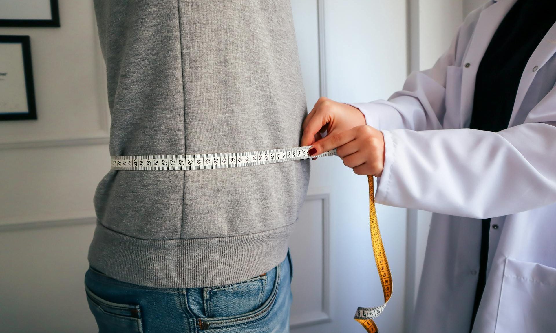 Doctor measuring the waist circumference of man