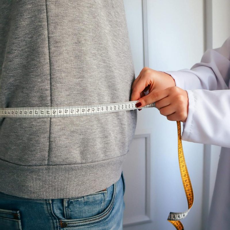 Doctor measuring the waist circumference of man