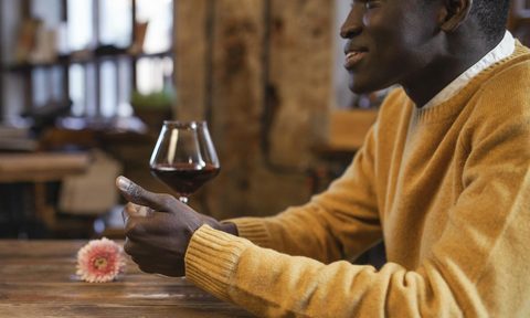 Man wearing a yellow sweater drinking wine