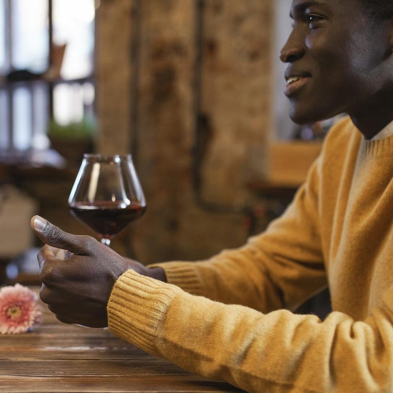 Man wearing a yellow sweater drinking wine