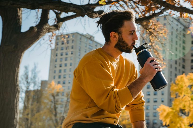 Man in a yellow shirt sitting outside sipping his water bottle