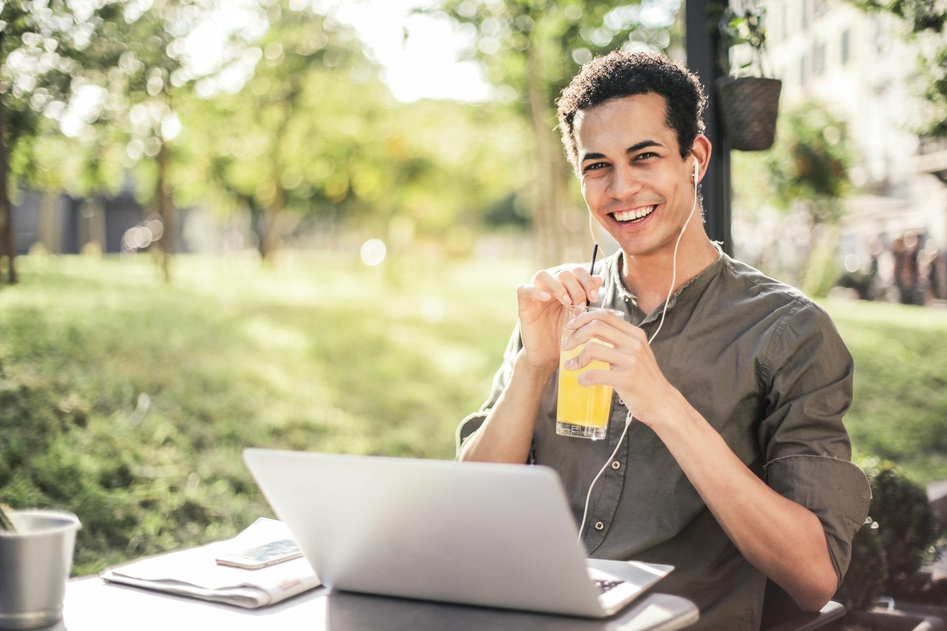 Man sitting outside with laptop and drink