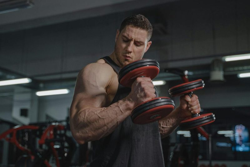man big muscles lifting dumbbells weights exercise hammer curl Zottman curl in gym