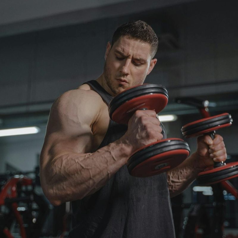 man big muscles lifting dumbbells weights exercise hammer curl Zottman curl in gym