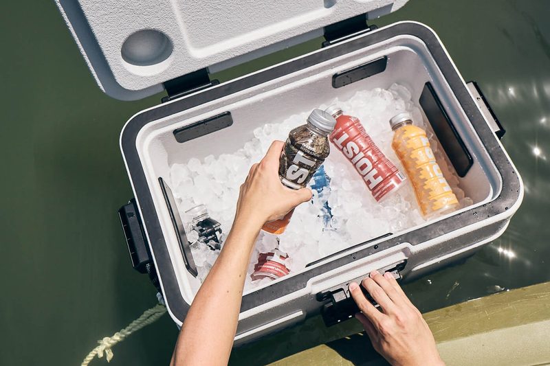 Hands reaching into an ice-filled floating cooler.