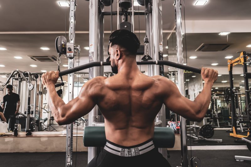 Fit man on lat pulldown machine at the health club. Work out on Pulldown Weight Machine