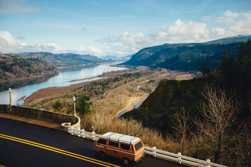 Yellow campervan on a bridge overlooking a river.