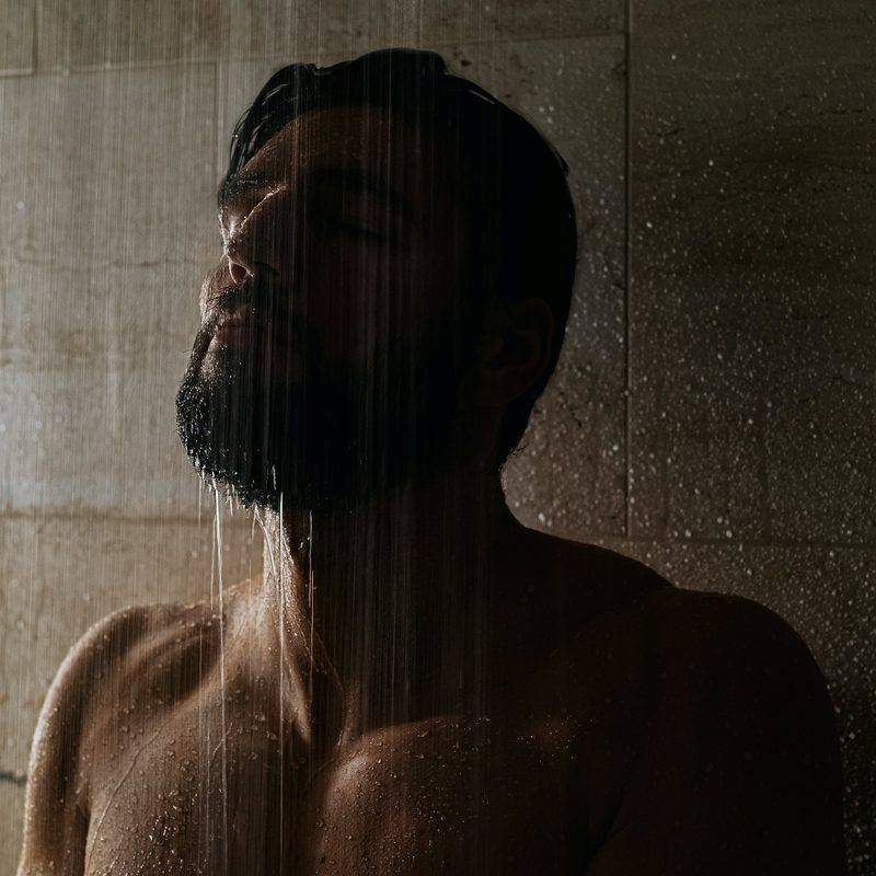 Man in shower with water over his beard