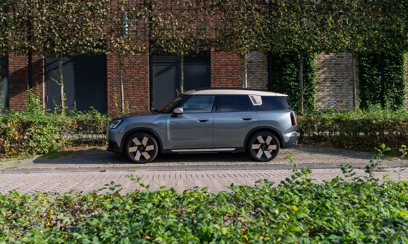 2025 all-electric MINI Countryman ALL4 SE parked on a brick street in front of a brick building with greenery on the building and foreground.