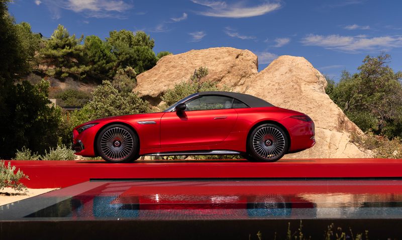 2026 Mercedes-Maybach SL 680 Monogram Series red and black on a red platform next to a swimming pool left profile with top up.