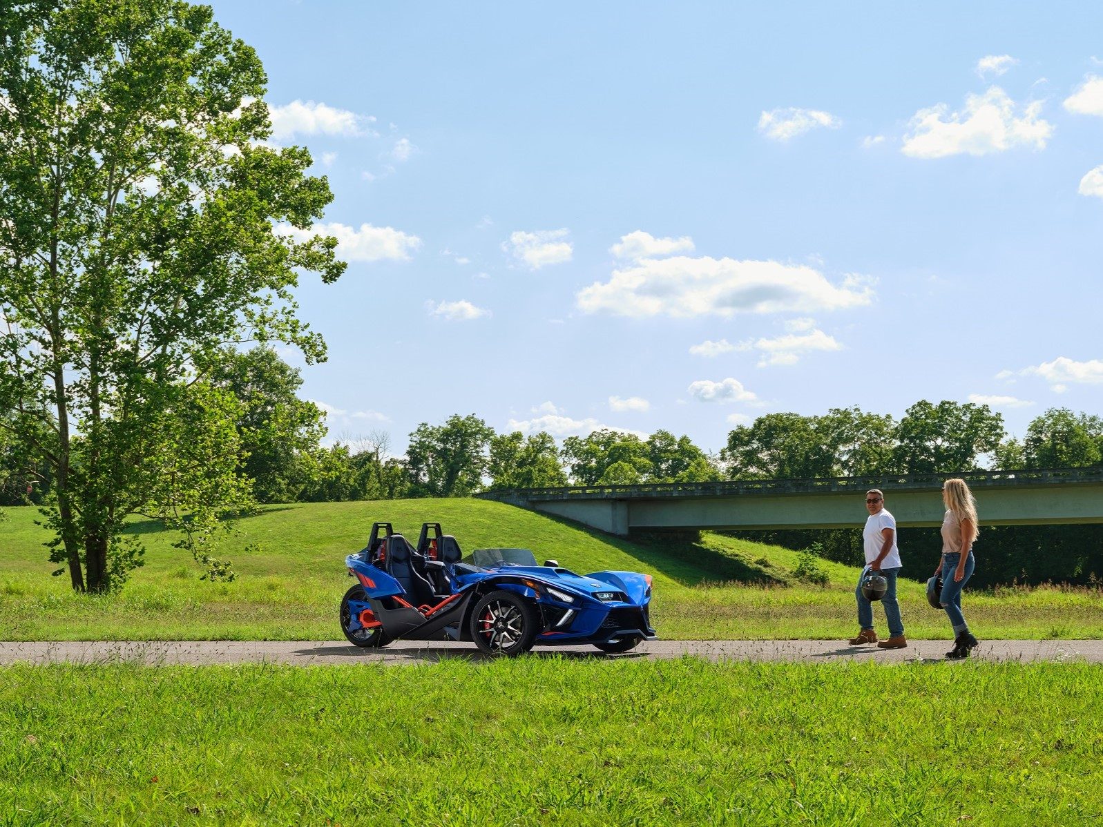 Couple getting into Polaris Slingshot R out on the open road