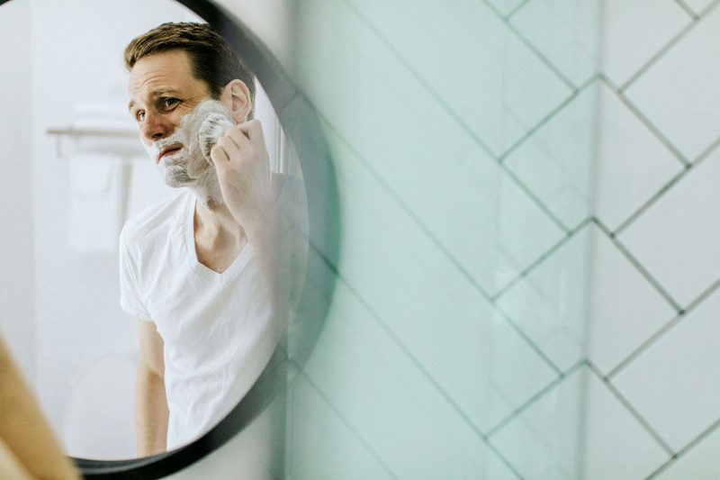 Man applying shaving cream in mirror