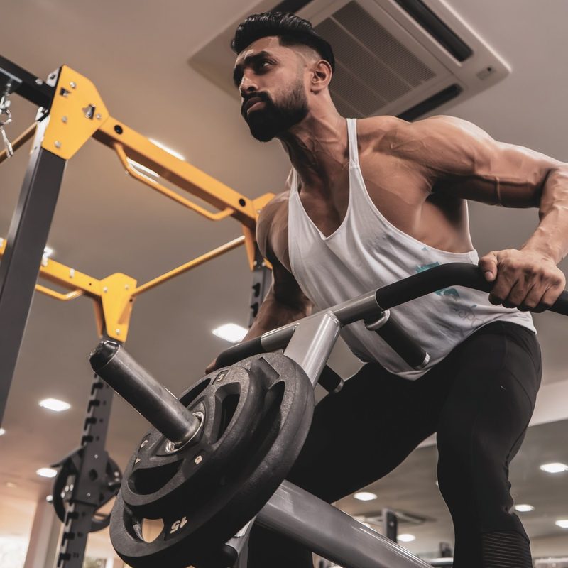 Guy in gym using machine to do the T-bar row exercise