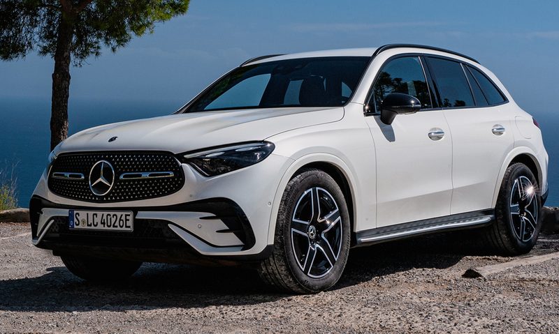 White 2025 Mercedes-Benz GLC 350e 4MATIC SUV parked on a stone parking lot with ocean in the background.