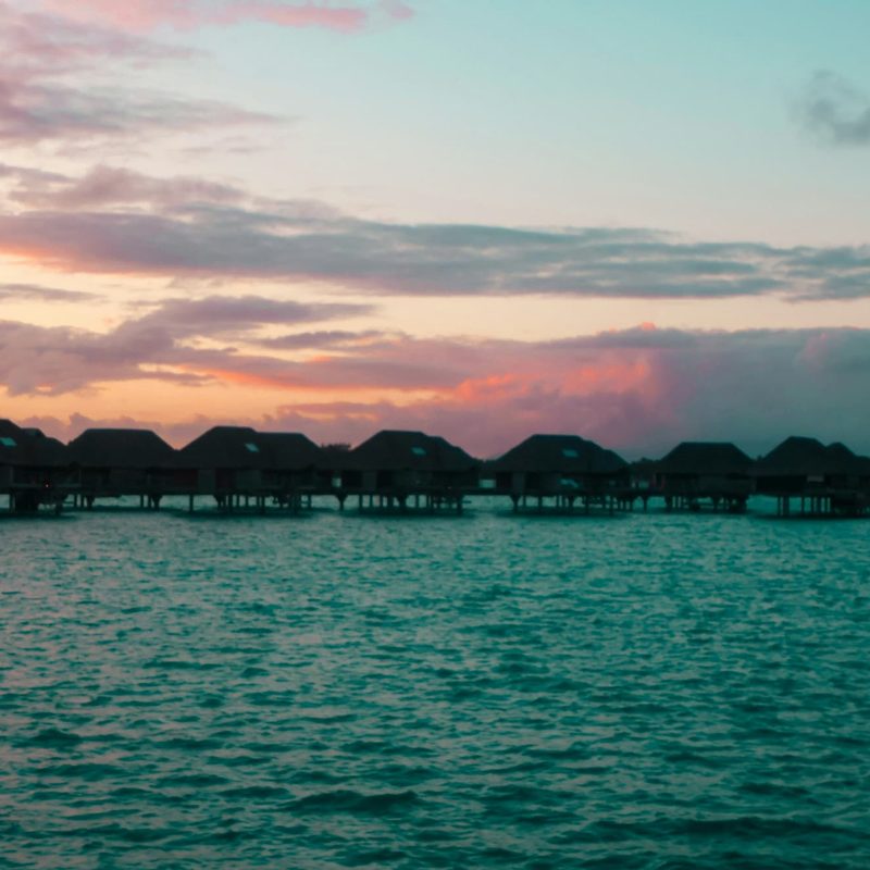 A body of water shown during sunset with overwater bungalows on it, in Bora Bora, French Polynesia