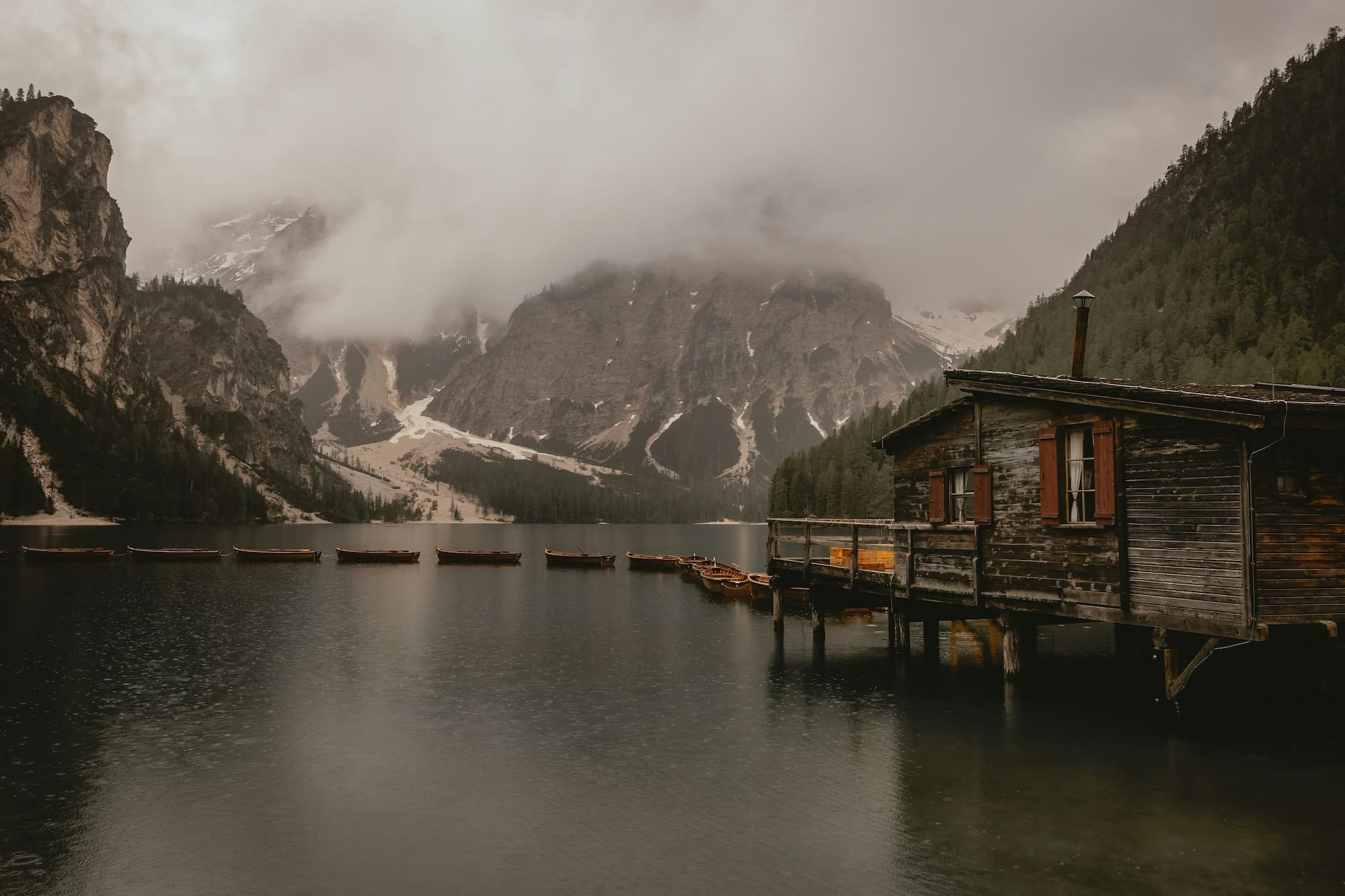 a cabin on a lake with mountains in the background