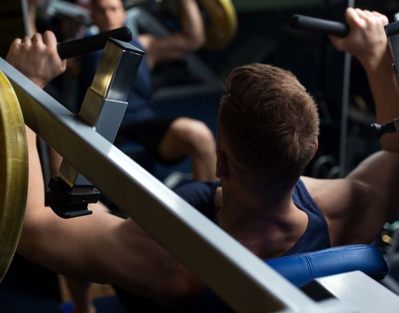Man using a chest press from behind