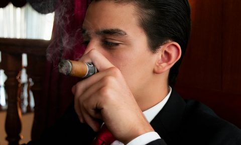 Man in suit smoking cigar in a lounge, relaxing.