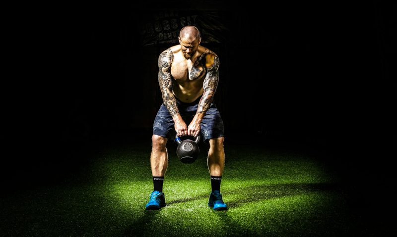 man swinging kettlebell with shorts blue shoes black background kettlebell swing pexels