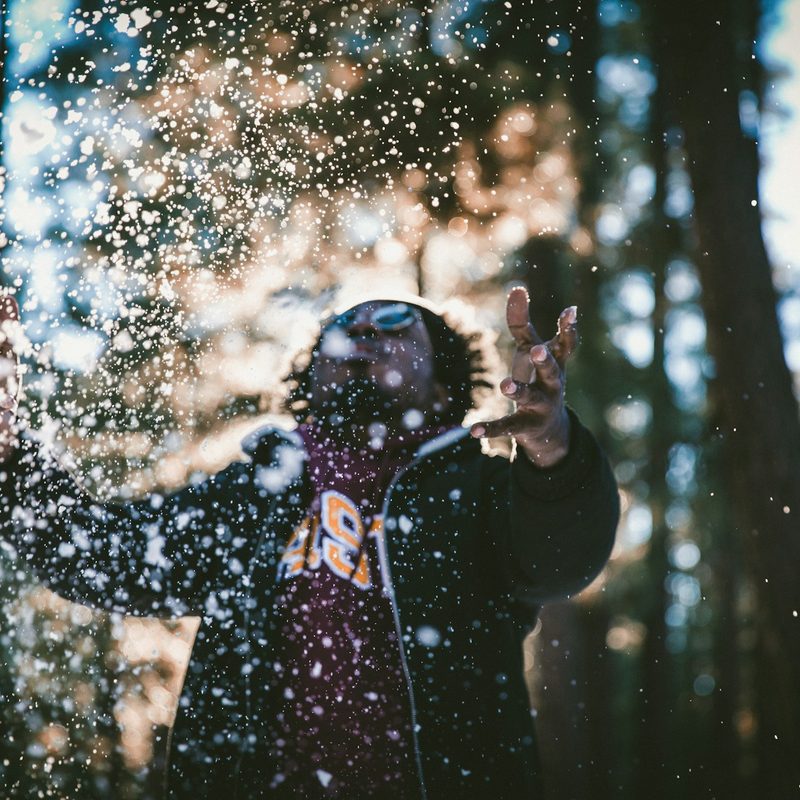 Man outside in the cold, throwing snow in the air.