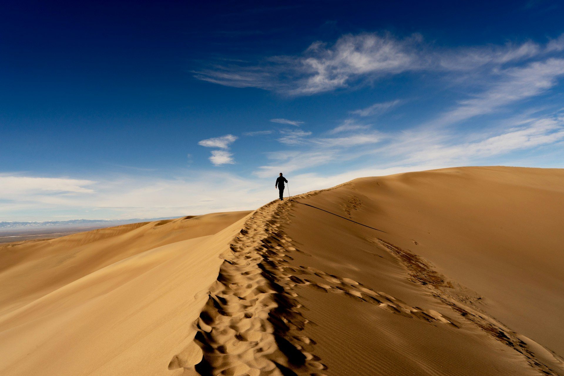 A person walking on the ridge of a sand dune in a national park