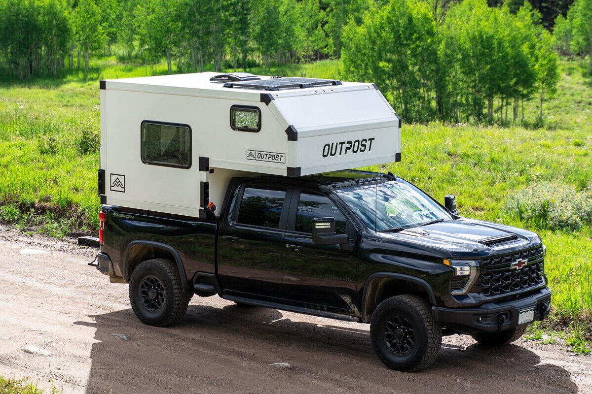 Front corner view of Outpost Campers' Outpost 6.5 truck camper mounted on a black Chevy pickup truck.