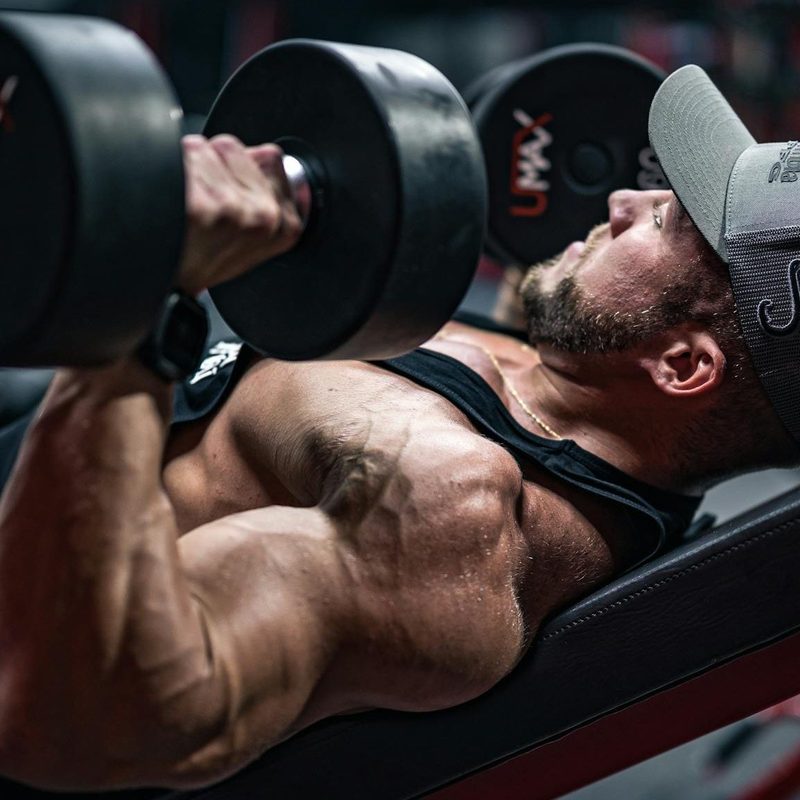 Man laying on workout bench doing chest presses with dumbbells