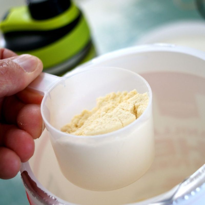 person scooping protein powder out of canister