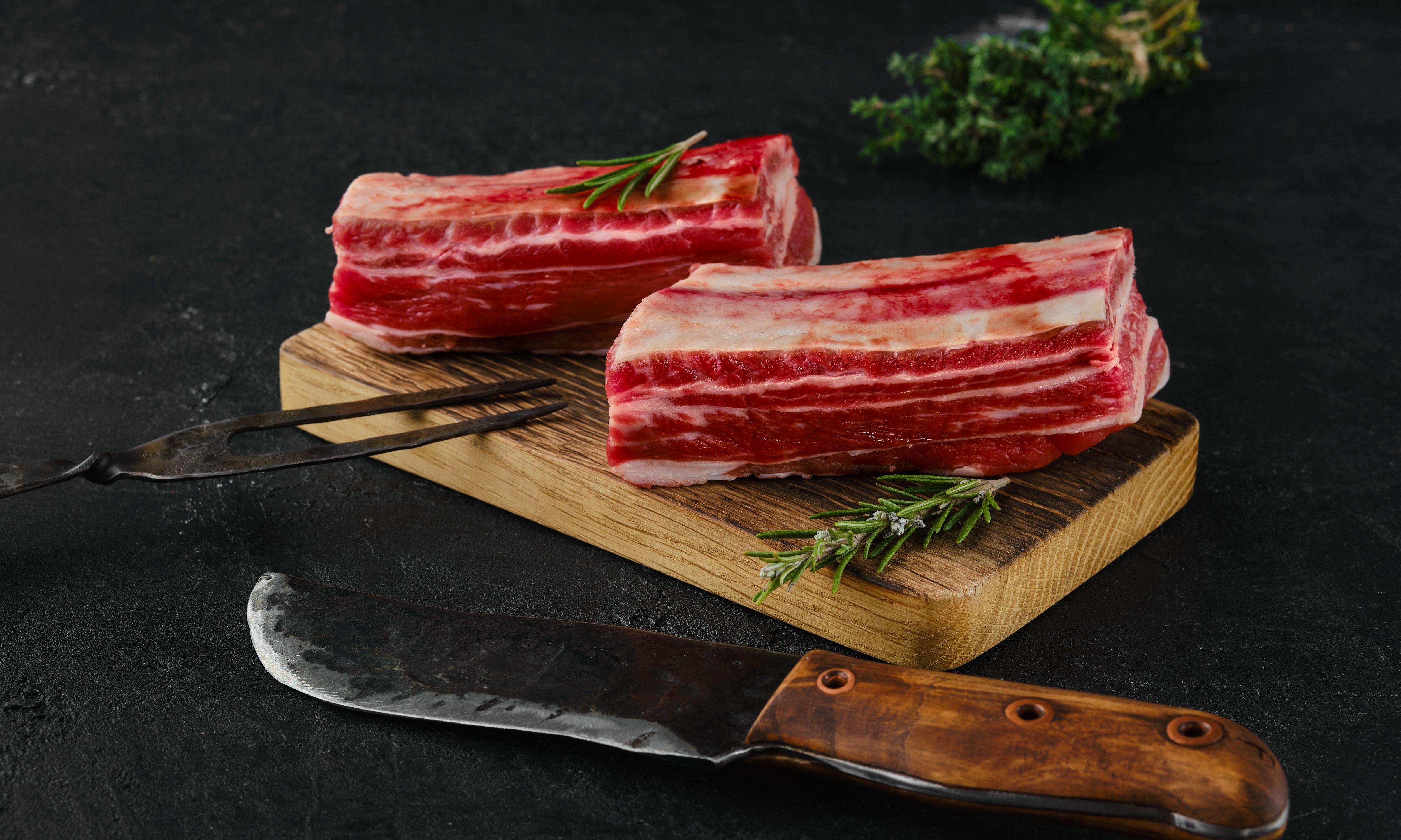 Raw beef short ribs, bone in on dark background