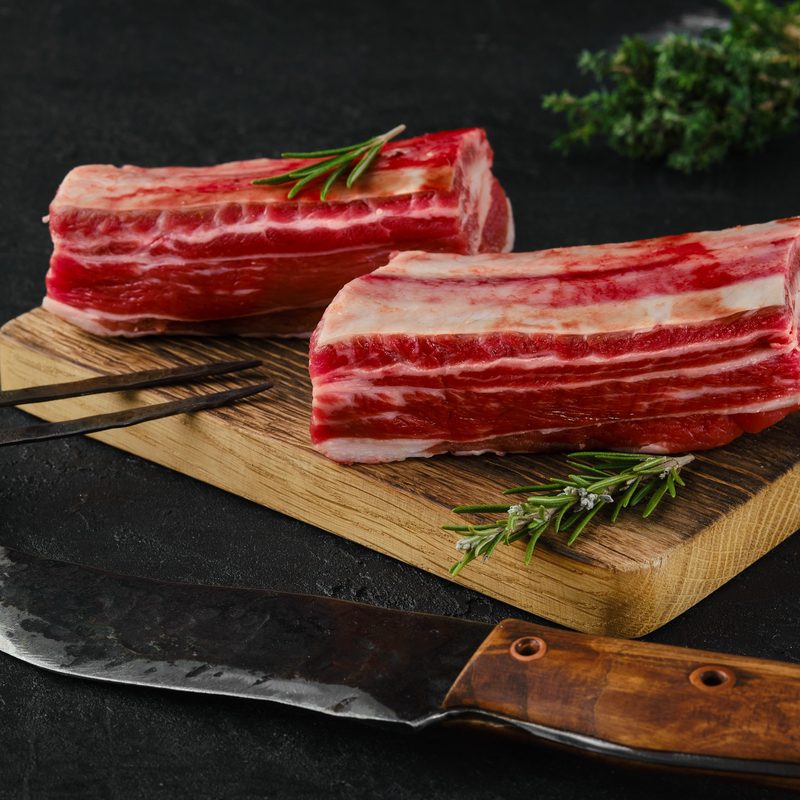Raw beef short ribs, bone in on dark background