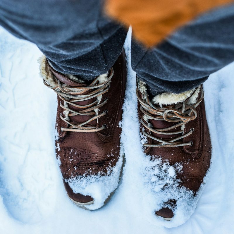 Closeup of man's feet wearing insulated winter boots in the snow.