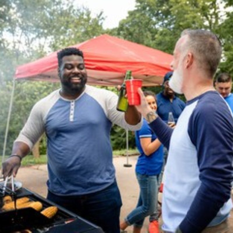 A tailgating party in the parking lot with people cooking food.