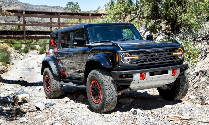 2024 Ford Bronco Raptor Black Edition ascending a rocky incline in the desert.