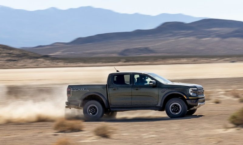 2025 Ford Ranger Raptor racing across flat desert.