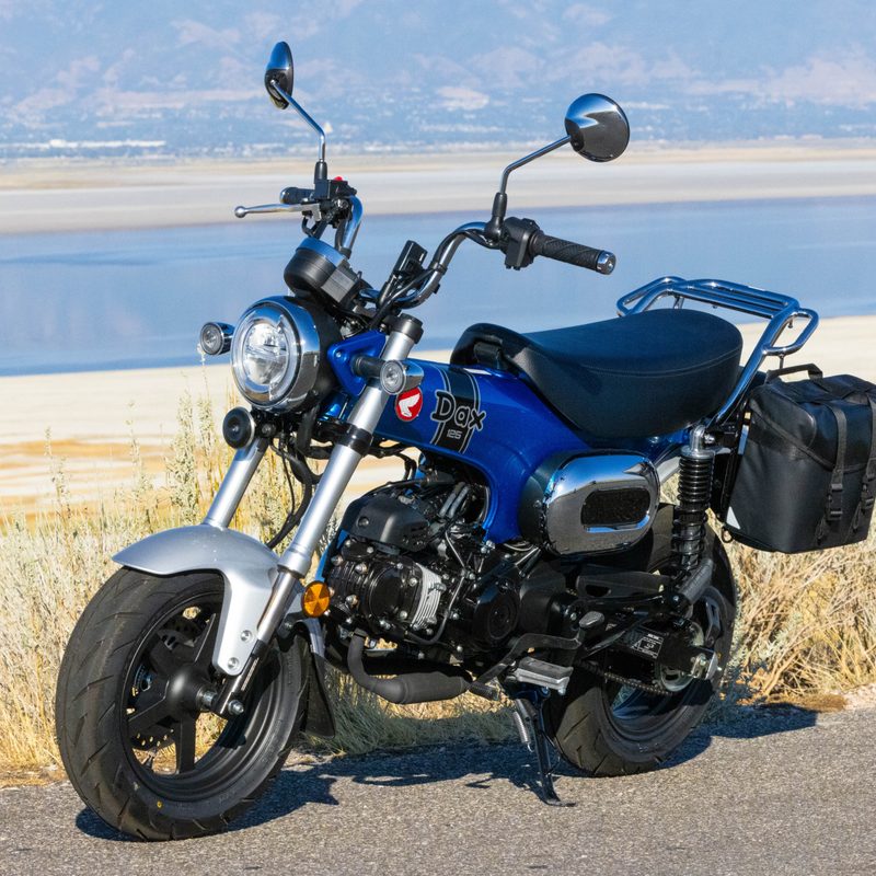 2025 Honda Daz 125 parked on the side of the road with water in the background.